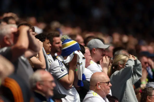 Leeds fans put their hands to their head in disbelief.