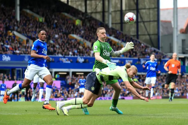 Everton goalkeeper Jordan Pickford challenges Manchester City striker Erling Haaland