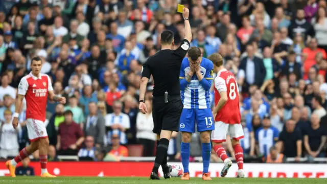 Referee Andy Madley shows a yellow card to Pascal Gross of Brighton during their game against Arsenal