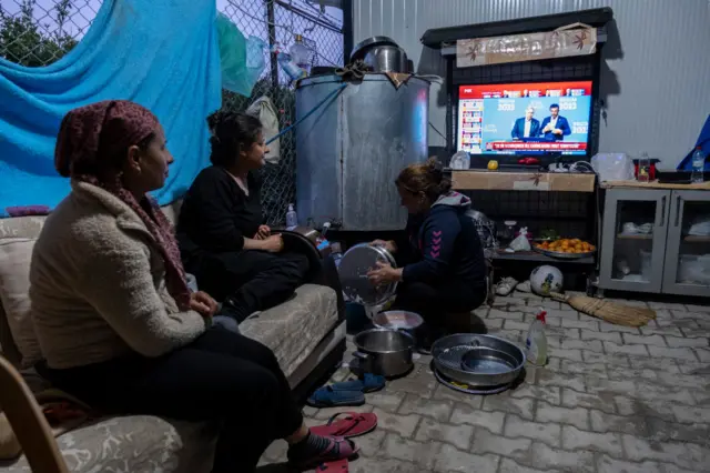 The Dinar family watches the election results in their tents on 14 May 2023 in Antakya, Turkey