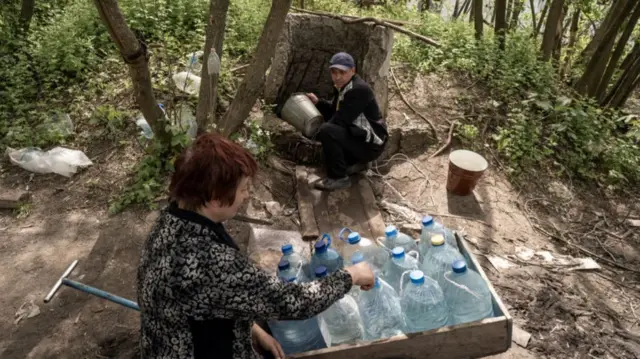 People gather water from a well in Chasiv Yar on 14 May