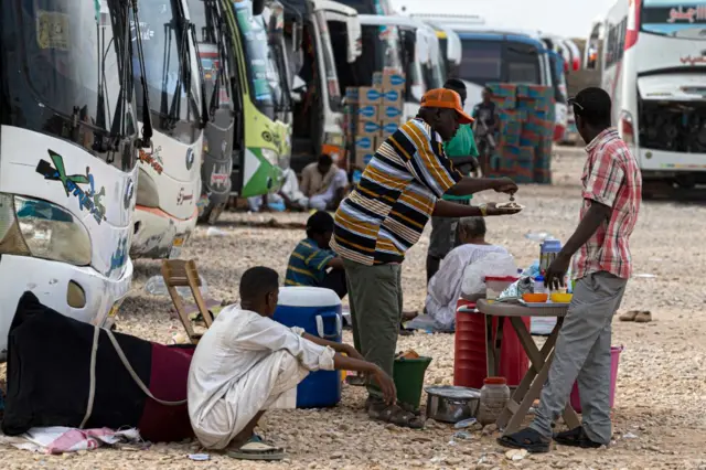 Sudanese drivers rest by their buses after transporting evacuees from Sudan into Egypt, in Wadi Karkar village near Aswan on May 14, 2023