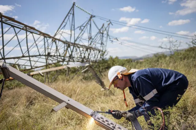 A worker cuts a section of a collapsed pylon in Pretoria on April 12, 2023.