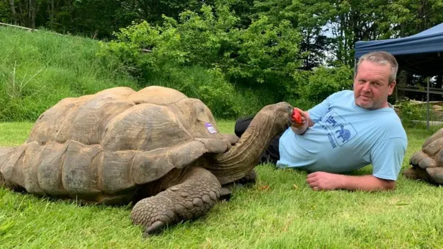 An Aldabra Tortoise and its owner Adrian Graham