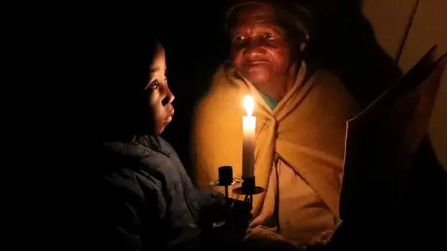 During a power cut in South Africa in 2021, Cecilia Nkosi talks to her great-grandson Smangaliso at home in Soweto.