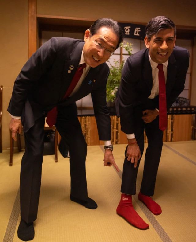 Fumio Kishida pointing at Rishi Sunak's socks