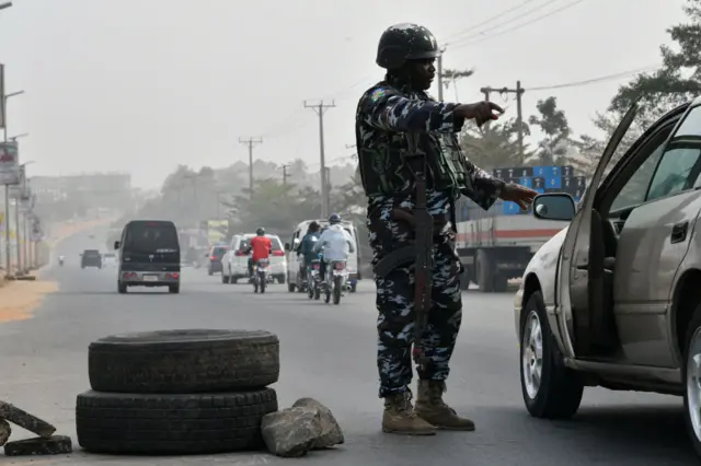 A police officer stops a car at a check point to check the activities of criminals and unknown gunmen ahead of the February 25 presidential election at Awka in Anambra State,