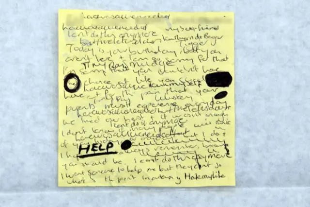 Black ink handwritting on a yellow post it note shown to jurors in the Lucy Letby trial