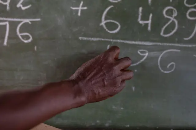 A woman writes on a blackboard at an elementary school in Mozambique - archive shot