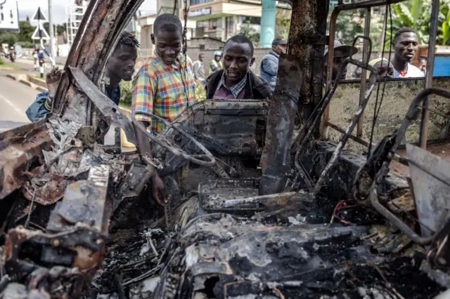 Bystanders observe a bus burnt by protesters during riots in Nairobi - 2 May 2023