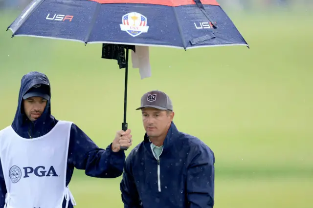Bryson DeChambeau shelters under a Ryder Cup umbrella