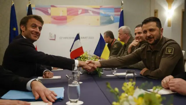 Ukraine's President Volodymyr Zelensky (R) shakes hands with France's President Emmanuel Macron