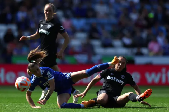 Leicester and West Ham players battle for the ball on the floor.