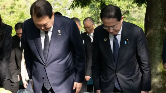 Yook Seok-yeol and Fumio Kishida bow their heads in front of a war cenotaph in Hiroshima.