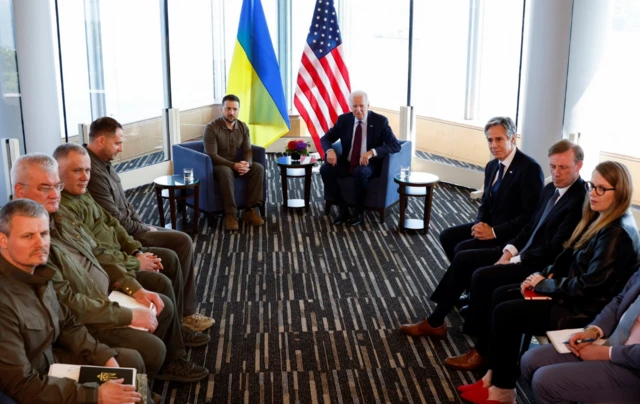 Ukrainian President Volodymyr Zelensky and US President Joe Biden sit at the front of a room facing officials from both nations