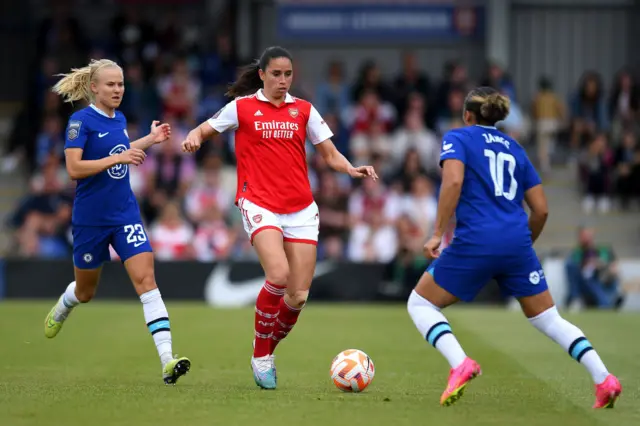 Rafaelle Souza runs with the ball whilst under pressure from Pernille Harder and Lauren James