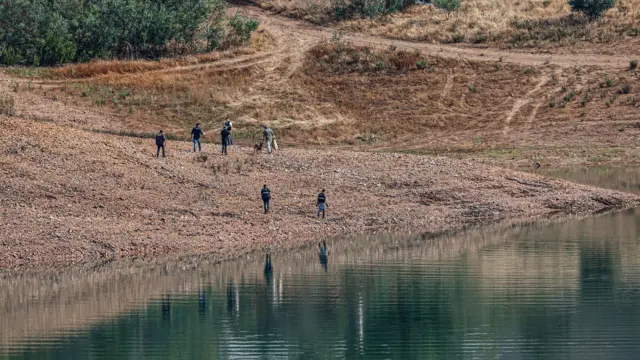 Portuguese authorities from the Judicial Police (PJ) criminal investigation unit search the shore of the reservoir