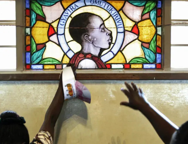 Christian pilgrims reach out to touch a stained glass window with the image of one of the Ugandan martyrs at the Catholic Basilica Church of the Uganda Martyrs a day before the Ugandan national Martyrs Day holiday in 2005 in Namugongo, Uganda