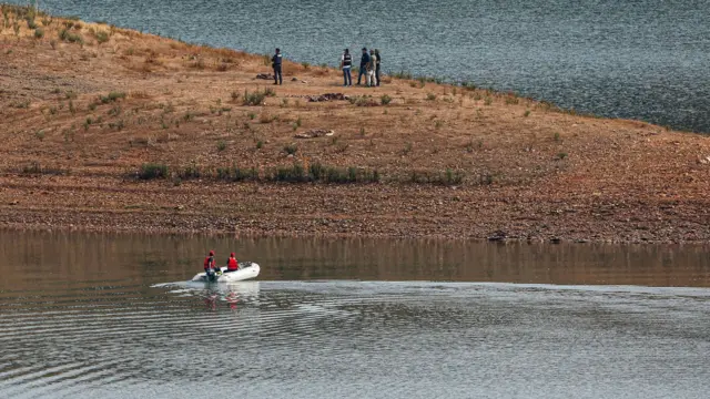 An inflatable boat searches the waters of the reservoir