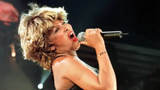 Tina Turner sings into a microphone