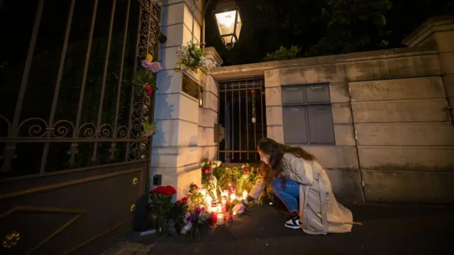 A woman lights a candle at a site of tributes for Tina Turner