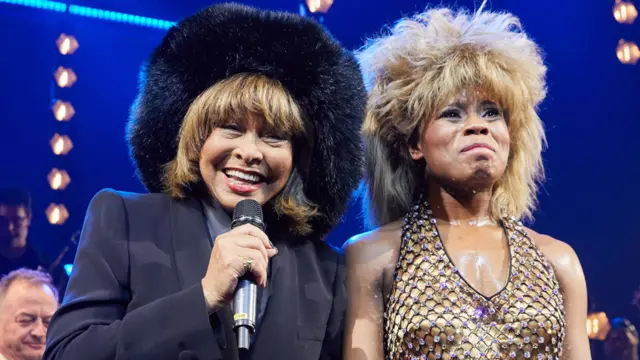 Tina Turner speaks on stage alongside Kristina Love