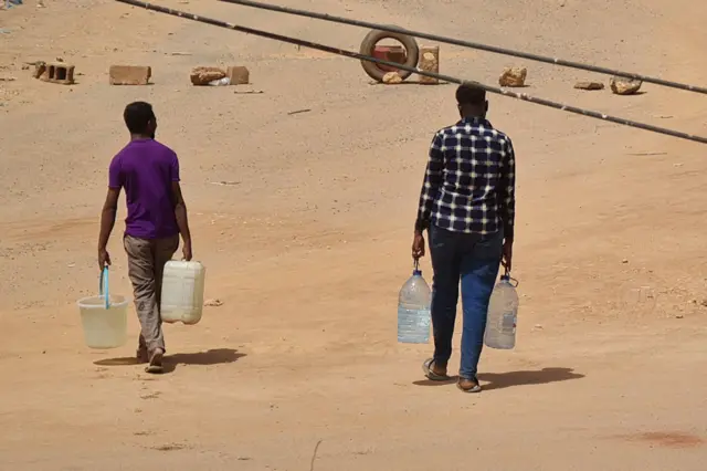 Men carry bottles of water back to their home in Khartoum, Sudan - 25 May 2023,