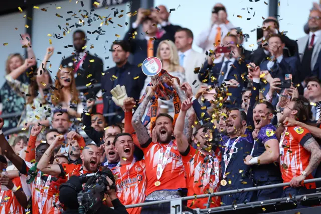 Sonny Bradley lifts the play-off trophy aloft for Luton