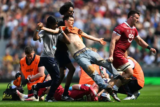 A protestor is escorted off the pitch