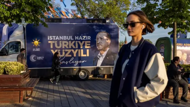 People walk past a campaign vehicle carrying a picture of Turkish President Tayyip Erdogan and a slogan that reads "Turkey’s century is starting. Istanbul is ready”