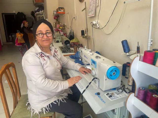 Binnaz sits at her sewing machine