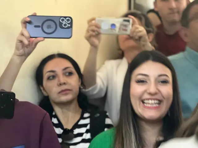 Voters wait with smart phones as opposition candidate Kemal Kilicdaroglu makes an appearance