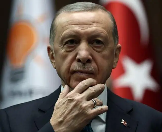 A picture of Recep Tayyip Erdogan, shown with a pensive look on his face with his right hand held at his chin