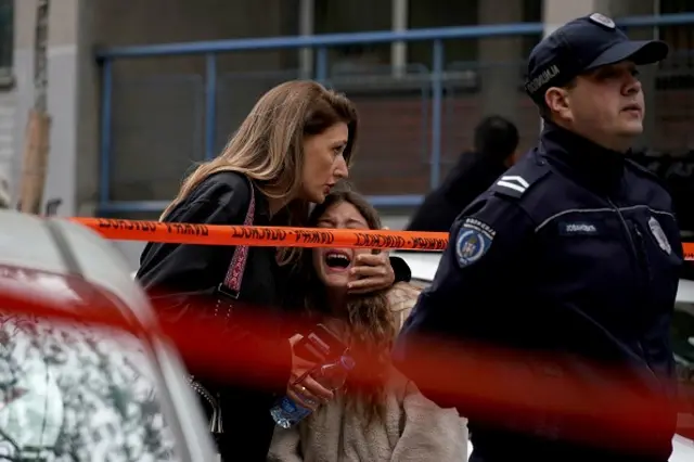 A parent escorts her child following a shooting at a school in the capital Belgrade on May 3, 2023