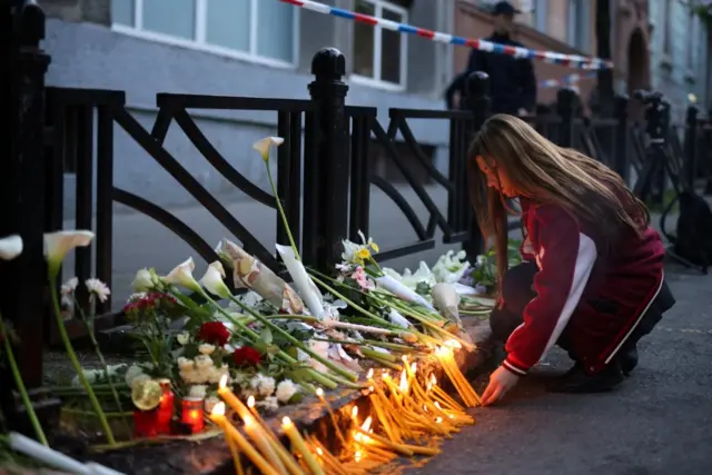 A child lights a candle in front of her school after the shooting