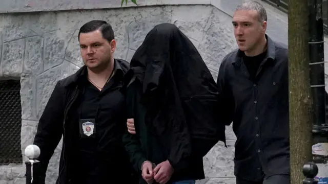 Police officers escort a minor, a seventh grade student who is suspected of firing several shots at a school in the capital Belgrade on May 3, 2023.