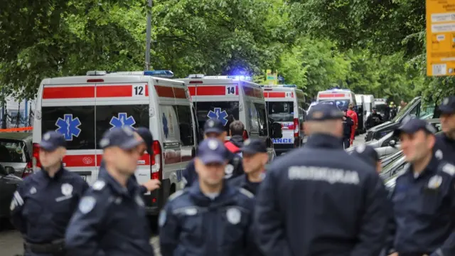 Police officers stand in front of ambulances