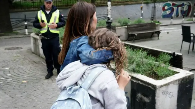 A woman wraps her arm a girl outside the school