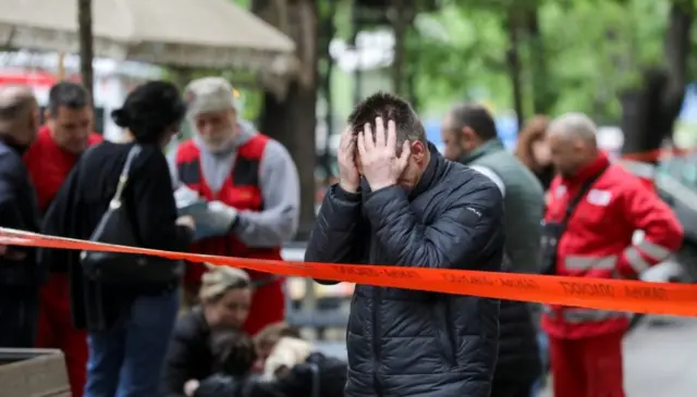 Man holds his head in his hands behind a police cordon, Belgrade