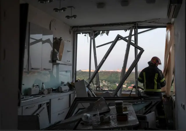 A rescuer works inside a damaged apartment building