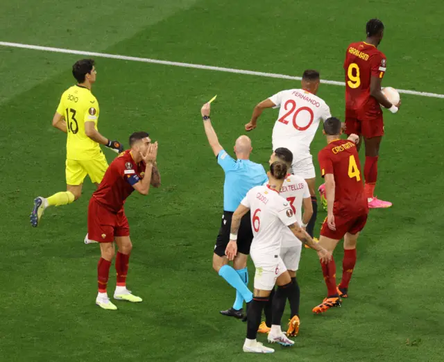 Referee Anthony Taylor shows a yellow card to Lorenzo Pellegrini