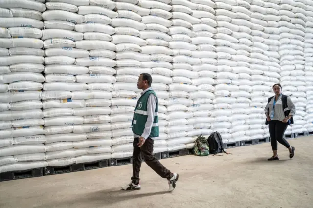 World Food Programme (WFP) staff walk past bags of wheat at a warehouse in Adama, Ethiopia, on January 12, 2023.