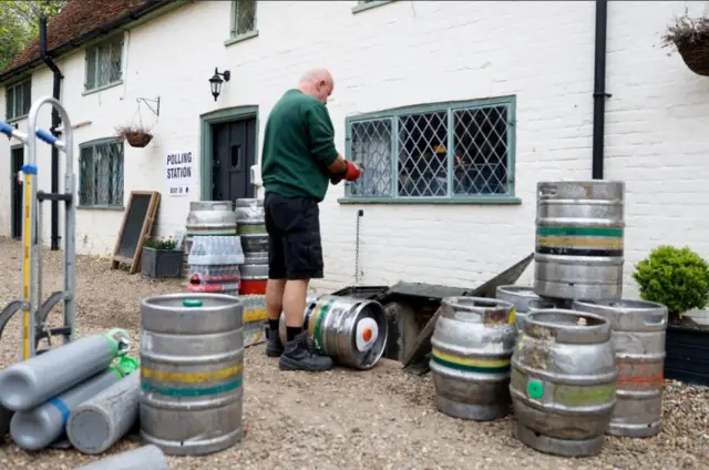 A man delivers stock to The Brocket Arms pub, which is acting as a polling station for local elections in Ayot St Lawrence, Britain