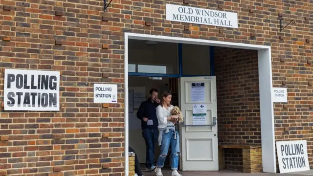 Voters leave a polling station with a dog