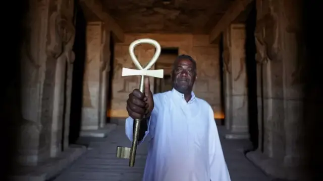 A man holds an enormous golden key at a temple in Egypt