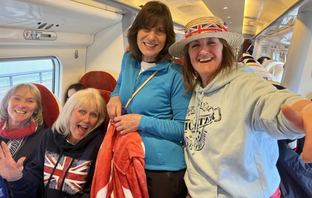 Four women pose for a selfie in a train carriage