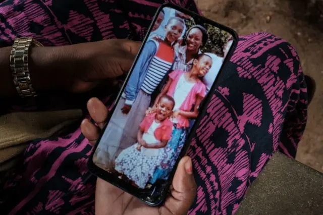 A woman holds her phone showing family members.