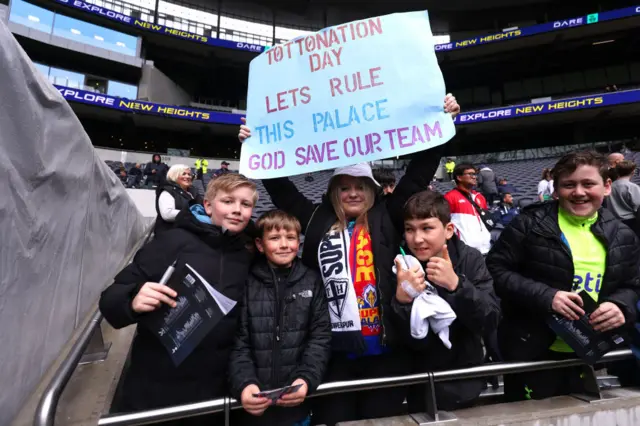 Tottenham fan holding a banner that says "Tottonation Day. Let's rule this Palace. God save our team"