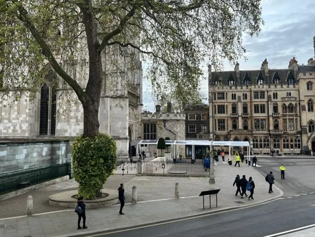 The scene outside Westminster Abbey - a few people walk along the pavement inside the abbey