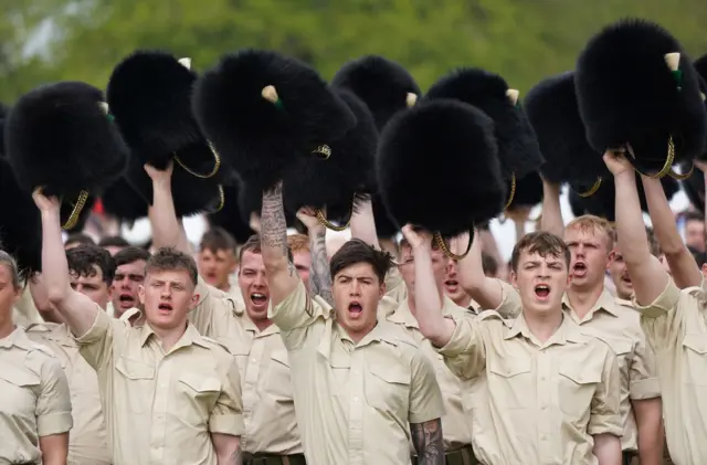 The Welsh Guards remove their hats as they give three cheers for King Charles in a rehearsal on Sunday